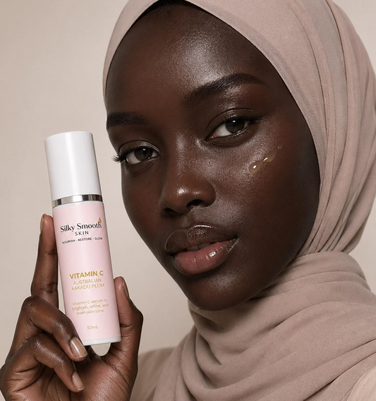 Woman in beige hijab holds Silky Smooth Skin Vitamin C serum, highlighting her glowing complexion with a drop on her cheek.